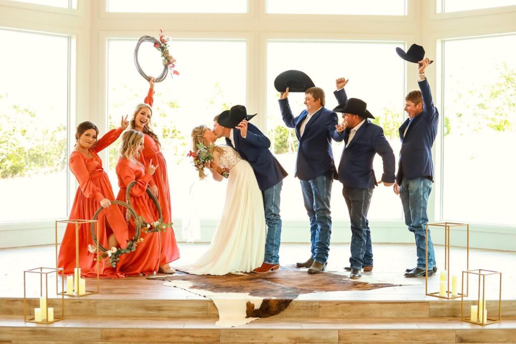 western bride and groom kissing while wedding party cheers