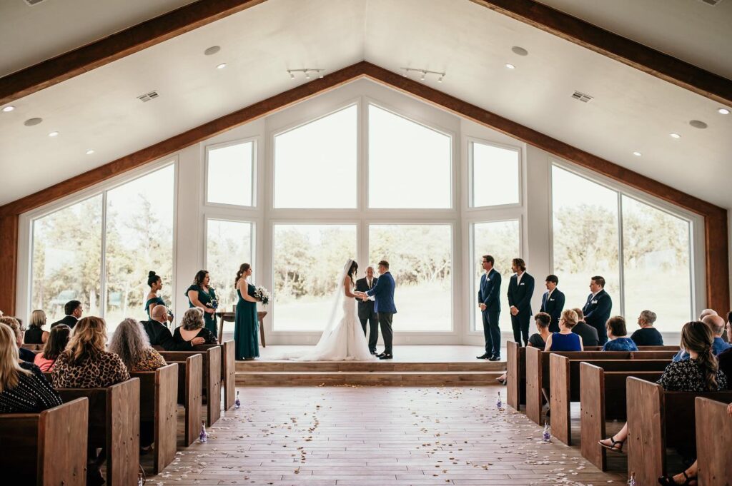 wedding ceremony in spacious chapel with large windows