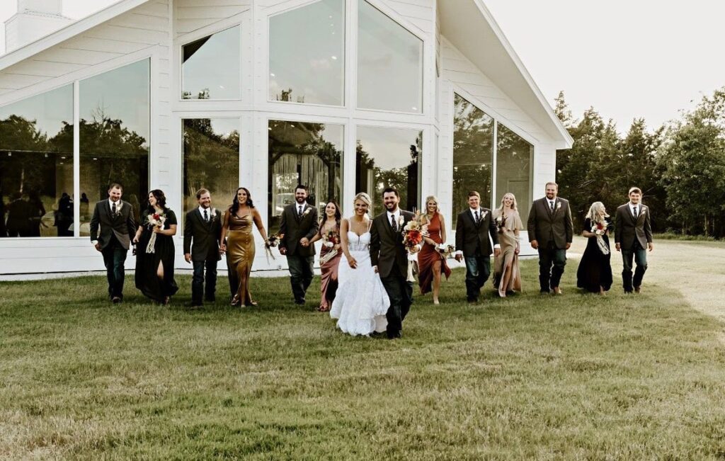 bride and groom walking in front of wedding venue with wedding party