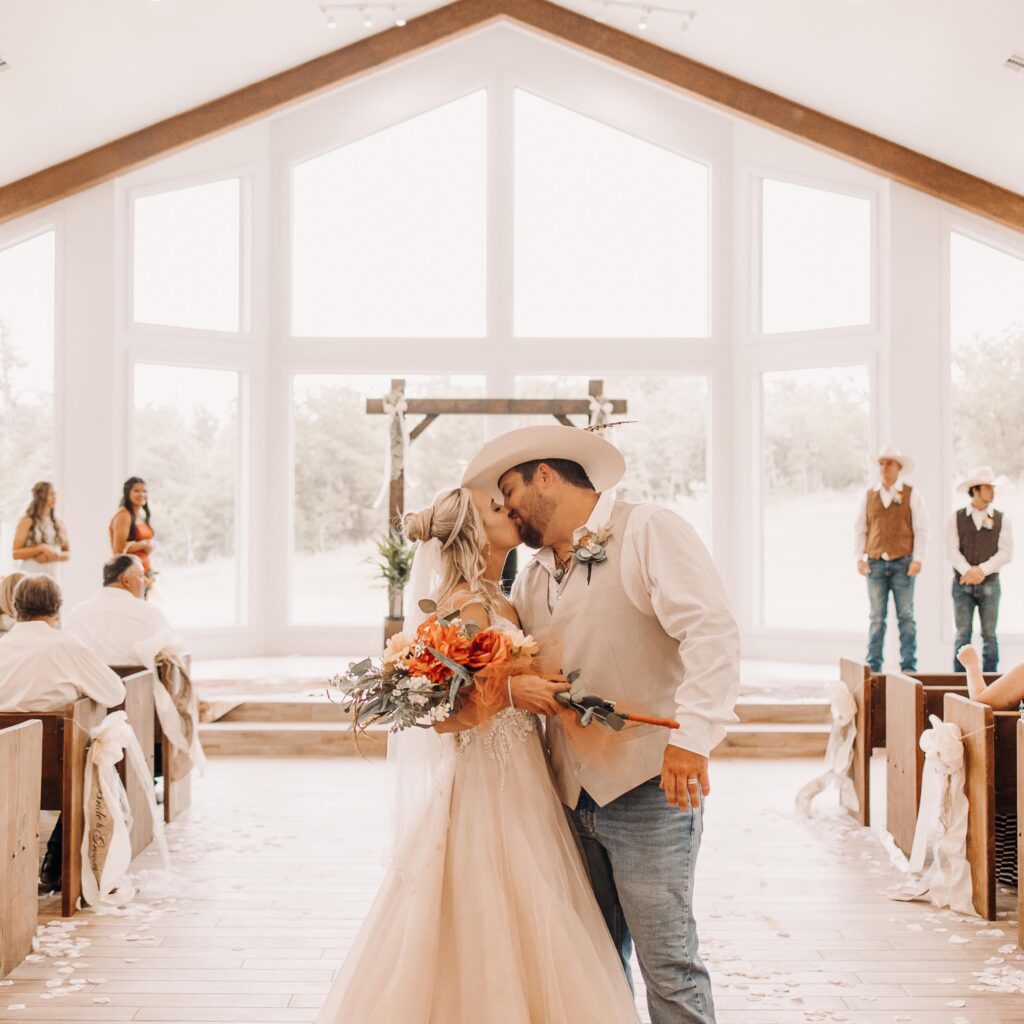 bride and groom kissing at end of aisle